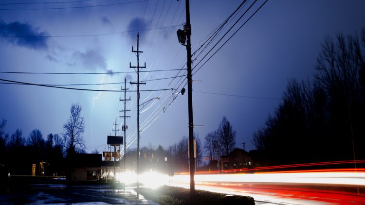Traffic moves by under the electrical storm, lighting, light and energy coming from all around